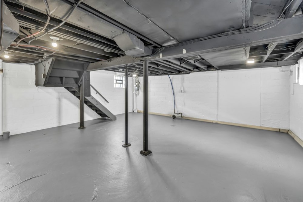 Unfinished basement with exposed floor joists and support posts